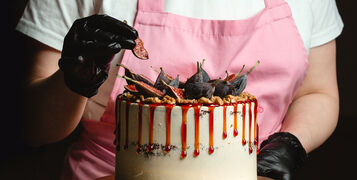 woman adding fig piece on classic cake decorated with figs and syrup